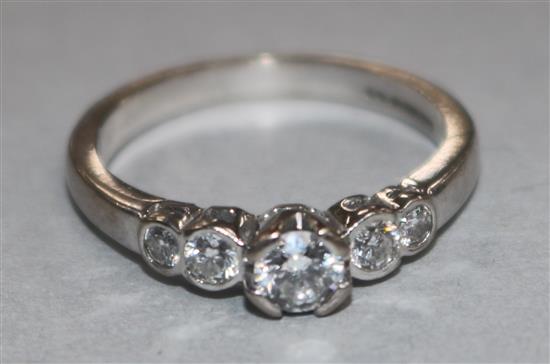 An 18ct gold and graduated five stone diamond half hoop ring, size L.